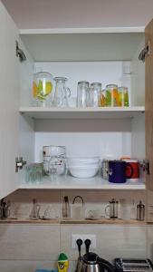 a kitchen shelf filled with lots of glass dishes at Cool Apartment Radauti in Rădăuţi +30 photos