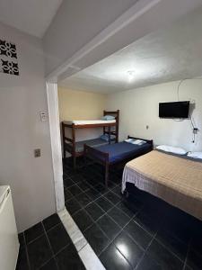 a room with two beds and a desk and a table at Residencial Sol Nascente in Porto Seguro