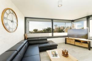 a living room with a black leather couch and a large clock at Südstrand Bungalow in Burgtiefe auf Fehmarn 