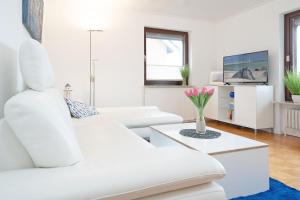 a white living room with a white couch and a table at Haus Hüttmann Sonnenblüte in Gremsmühlen