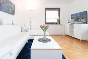 a white living room with a white couch and a table at Haus Hüttmann Sonnenblüte in Gremsmühlen