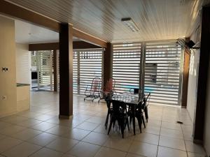 a dining room with a table and chairs and windows at Casa da piscina in Macapá