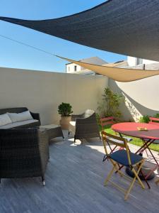 a patio with a table and chairs and an umbrella at La vie est belle à 10 minutes de La Rochelle in Saint-Xandre
