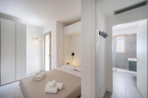 ein weißes Schlafzimmer mit einem Bett mit Handtüchern darauf in der Unterkunft ApartmentsGarda - Eleonora Studio 7 in Garda