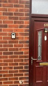 a brick building with a red door and a brick wall at Cosy 3 bedroom house in Leigh