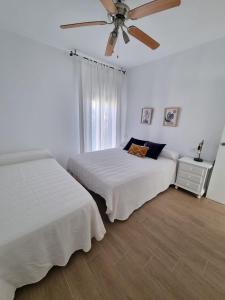 a bedroom with two beds and a ceiling fan at Apartamento de lujo en Playa de Regla in Chipiona
