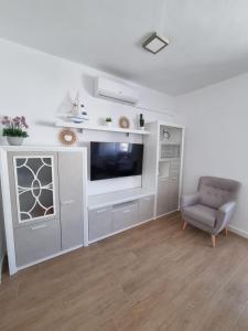 a living room with a television and a chair at Apartamento de lujo en Playa de Regla in Chipiona
