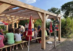 un gruppo di persone seduti sotto un pergolato di legno di Mini Camping Drentse Monden a Nieuw-Weerdinge