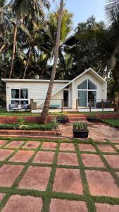 a white house with a palm tree in front of it at Sea Breeze, Guhagar in Guhagar