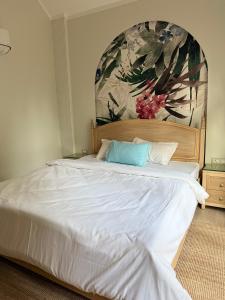 a bedroom with a large white bed with a painting on the wall at Sea Breeze, Guhagar in Guhagar