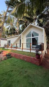 a white house with a palm tree in a yard at Sea Breeze, Guhagar in Guhagar