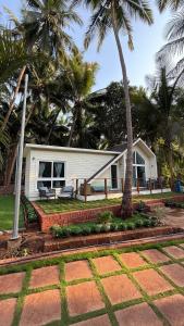 a white house with palm trees in front of it at Sea Breeze, Guhagar in Guhagar