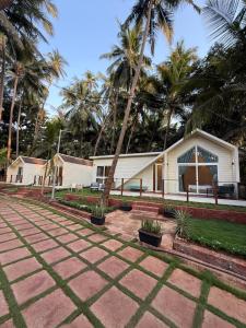 a house with palm trees in front of it at Sea Breeze, Guhagar in Guhagar