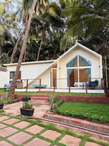a white house with a palm tree in front of it at Sea Breeze, Guhagar in Guhagar