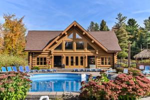 a log cabin with a pool and a house at Chalet 20 Ours, Lac Fiddler in Mille-Isles