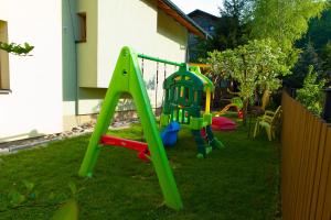 Un parque infantil en un patio con un columpio verde. en Willa Nowa Osada, en Wisła