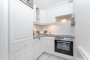 a white kitchen with white cabinets and an oven at Haus Meeresgruß Relax in Grömitz