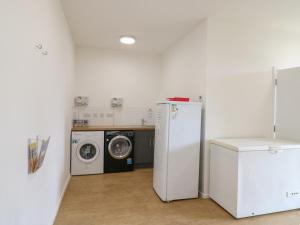 a laundry room with a refrigerator and a washing machine at Bluebelle Cow Shed 5 in Woodbridge