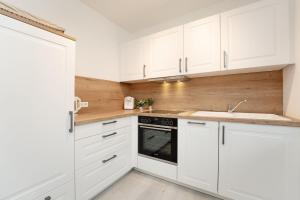 a white kitchen with white cabinets and a sink at Ferienwohnung Jankar in Timmendorfer Strand