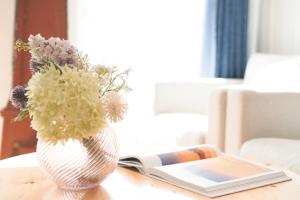 a vase with flowers on a table next to a book at Ferienhaus Seepferdchen in Fehmarn +31 photos