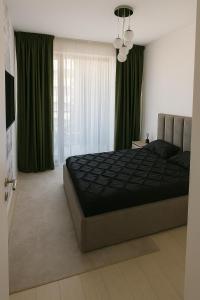 a bedroom with a large bed with green curtains at Herăstrău WIN Résidence No 4 in Bucharest