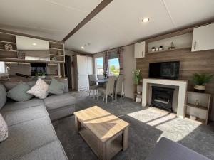 a living room with a couch and a fireplace at Oak Village 17 - HOT TUB Grange Leisure Park, Mablethorpe - Central heating, Pet friendly - Meadow Lakes Caravan & Lodge Hire in Mablethorpe