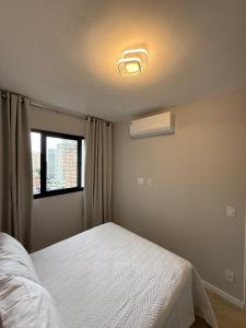 a bedroom with a white bed and a window at O melhor do Brooklin 1301 in Sao Paulo