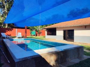 a swimming pool with a blue umbrella over it at Haus Independencia Guara Paraguay in Colonia Catorce de Mayo