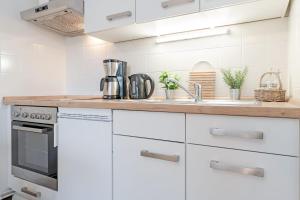 a kitchen with white cabinets and a sink at Haus Baltic Traumfabrik in Scharbeutz