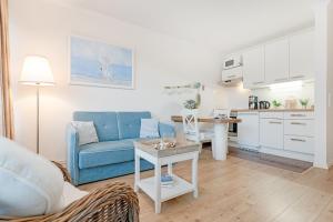 a living room with a blue couch and a kitchen at Haus Baltic Traumfabrik in Scharbeutz