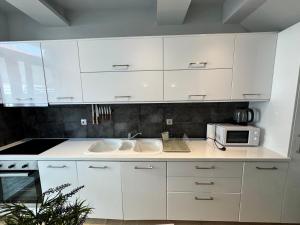 a white kitchen with a sink and a microwave at Delfi Home in Samos
