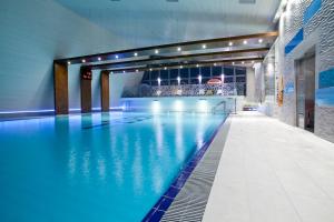 a large swimming pool with blue water in a building at Eden Resort & Spa in Mielno