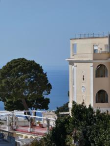 a building with a tree next to a building with a clock at Capresella luxury apartment in Capri