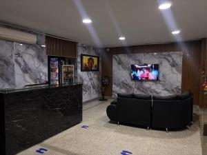 a lobby with a couch and a tv on a wall at Hotel Los Arcangeles in Cúcuta