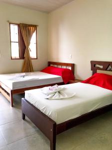 a bedroom with two beds with red sheets and a window at Hotel Diamante in Saravena