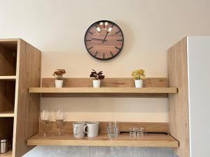 a clock on a wall above a shelf with glasses at Apartament Górna 20 in Łódź