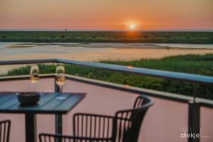 a table and chairs on a balcony with the sunset at Lütt Diekje in Westermarkelsdorf