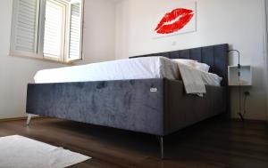 a large bed in a bedroom with a red lips painting on the wall at Dubrovnik Icy Guest House in Dubrovnik