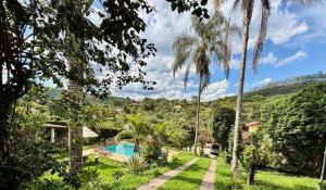 a resort with a swimming pool and palm trees at Sitio Julimari in Itabirito
