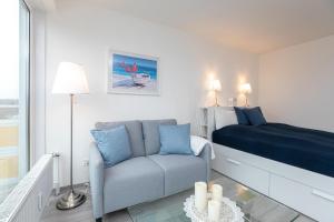 ein Schlafzimmer mit einem Bett, einer Couch und einem Stuhl in der Unterkunft Strandhotel Scharbeutz Dünenliebe in Scharbeutz
