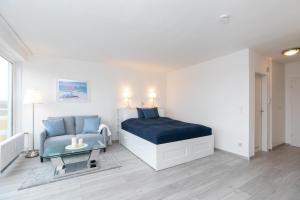 ein Schlafzimmer mit einem Bett, einer Couch und einem Tisch in der Unterkunft Strandhotel Scharbeutz Dünenliebe in Scharbeutz