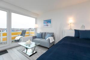 ein Schlafzimmer mit einem Bett und einer Couch und einem Fenster in der Unterkunft Strandhotel Scharbeutz Dünenliebe in Scharbeutz + 30 Fotos