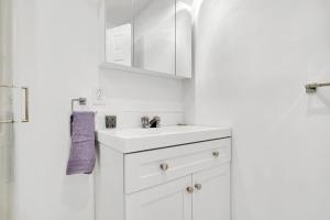 a white bathroom with a sink and a mirror at Elegance, Confort Et Detente in Montréal