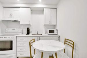 a white kitchen with a white table and chairs at Elegance, Confort Et Detente in Montréal