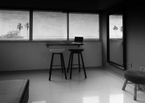 a room with a desk with a laptop and two stools at Alojamiento Lecheria PV1 in El Morro de Barcelona