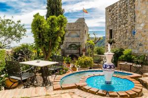 a fountain in the middle of a patio with a table at Hotel Castillo de Monda in Monda