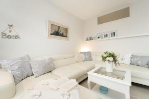 een witte woonkamer met een witte bank en een tafel bij Strandappartements am Leuchtturmweg Baltic-View in Kellenhusen