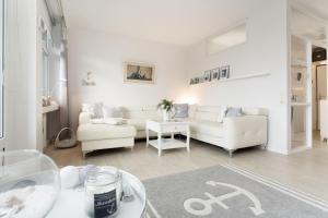 een witte woonkamer met een bank en een tafel bij Strandappartements am Leuchtturmweg Baltic-View in Kellenhusen