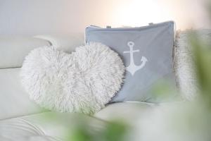 een kussen met een hart en een anker op een bank bij Strandappartements am Leuchtturmweg Baltic-View in Kellenhusen