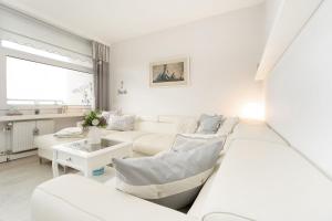 een witte woonkamer met een bank en een tafel bij Strandappartements am Leuchtturmweg Baltic-View in Kellenhusen +38 foto's